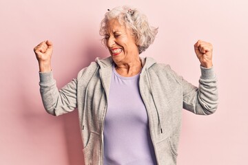 Senior grey-haired woman wearing casual sporty clothes very happy and excited doing winner gesture with arms raised, smiling and screaming for success. celebration concept.