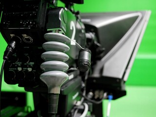 closeup of broadcast television studio camera with greenscreen at TV station.
