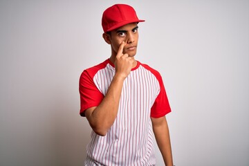 Young handsome african american sportsman wearing striped baseball t-shirt and cap Pointing to the eye watching you gesture, suspicious expression