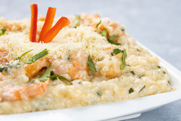 Risotto with shrimp served in a white bowl isolated on a rustic gray wooden background.