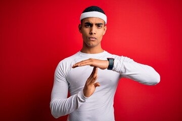 Young handsome african american sportsman wearing sportswear over red background Doing time out...
