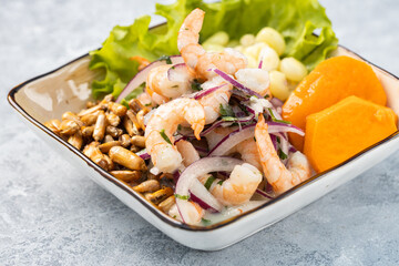 Shrimp ceviche served in a rustic bowl, isolated over a textured rustic gray wooden background.