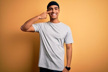 Handsome african american sportsman doing sport wearing sportswear over yellow background Pointing with hand finger to face and nose, smiling cheerful. Beauty concept