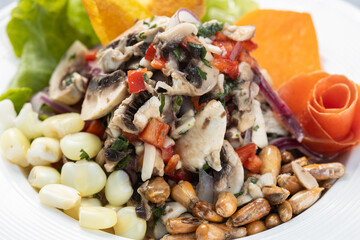 Vegetarian mushroom ceviche served with paprika, carrot, onion and corn, served on a white plate, isolated on a gray textured wooden backdrop.