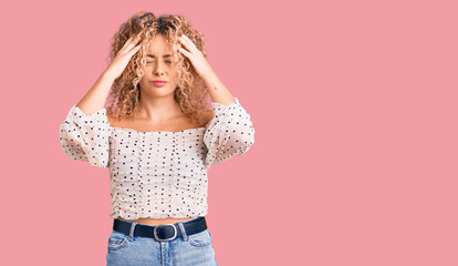 Young blonde woman with curly hair wearing casual clothes suffering from headache desperate and stressed because pain and migraine. hands on head.