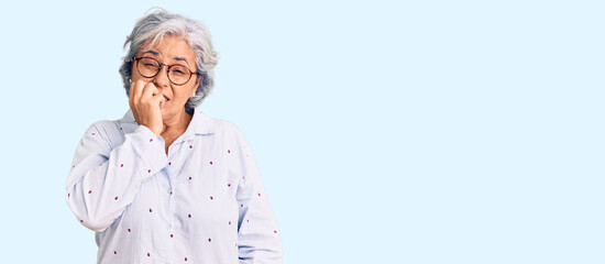 Senior woman with gray hair wearing casual business clothes and glasses looking stressed and nervous with hands on mouth biting nails. anxiety problem.
