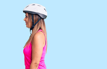 Young beautiful woman wearing bike helmet looking to side, relax profile pose with natural face with confident smile.