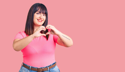 Young plus size woman wearing casual clothes smiling in love doing heart symbol shape with hands. romantic concept.