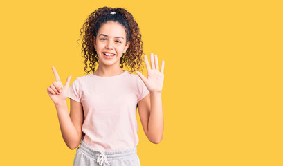 Beautiful kid girl with curly hair wearing casual clothes showing and pointing up with fingers...