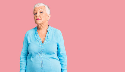 Senior beautiful woman with blue eyes and grey hair wearing summer dress relaxed with serious expression on face. simple and natural looking at the camera.