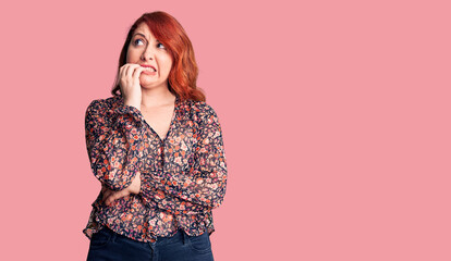 Young beautiful redhead woman wearing casual t-shirt looking stressed and nervous with hands on mouth biting nails. anxiety problem.