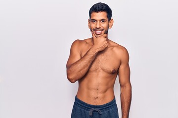 Fototapeta na wymiar Young latin man standing shirtless looking confident at the camera smiling with crossed arms and hand raised on chin. thinking positive.