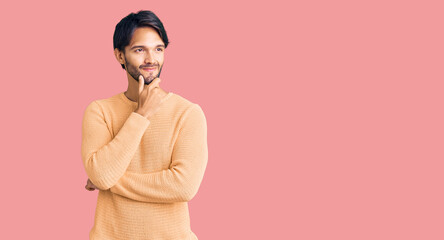 Handsome hispanic man wearing casual sweater with hand on chin thinking about question, pensive expression. smiling with thoughtful face. doubt concept.