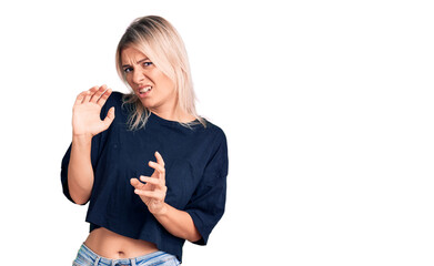 Young beautiful blonde woman wearing casual t-shirt disgusted expression, displeased and fearful...