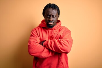 Young african american sporty man wearing sweatshirt with hoodie over yellow background skeptic and nervous, disapproving expression on face with crossed arms. Negative person.