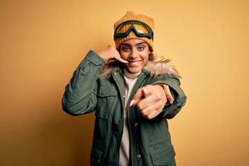 Young african american afro skier girl wearing snow sportswear and ski goggles smiling doing...