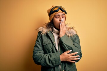 Young african american afro skier girl wearing snow sportswear and ski goggles bored yawning tired covering mouth with hand. Restless and sleepiness.