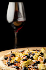 Homemade traditional capricciosa pizza with red wine glass