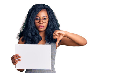 Beautiful african american woman holding blank empty banner with angry face, negative sign showing dislike with thumbs down, rejection concept