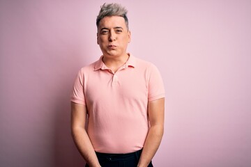 Young handsome modern man wearing casual pink t-shirt over isolated background puffing cheeks with funny face. Mouth inflated with air, crazy expression.
