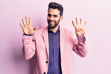 Young handsome man with beard wearing elegant jacket showing and pointing up with fingers number nine while smiling confident and happy.