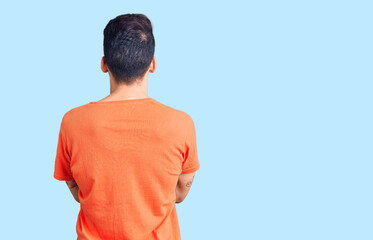 Young handsome man with beard wearing casual t-shirt standing backwards looking away with crossed...