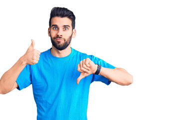 Young handsome man with beard wearing casual t-shirt doing thumbs up and down, disagreement and agreement expression. crazy conflict