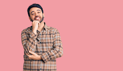 Young hispanic man wearing casual clothes looking confident at the camera smiling with crossed arms and hand raised on chin. thinking positive.