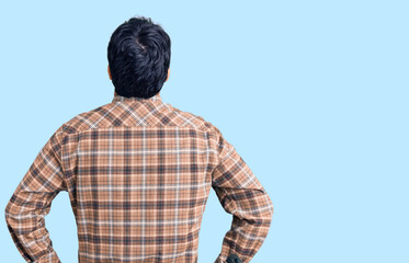 Young hispanic man wearing casual clothes standing backwards looking away with arms on body