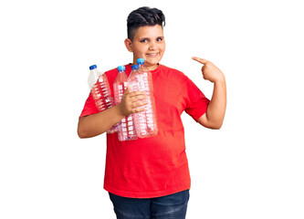 Little boy kid holding recycling plastic bottles pointing finger to one self smiling happy and proud