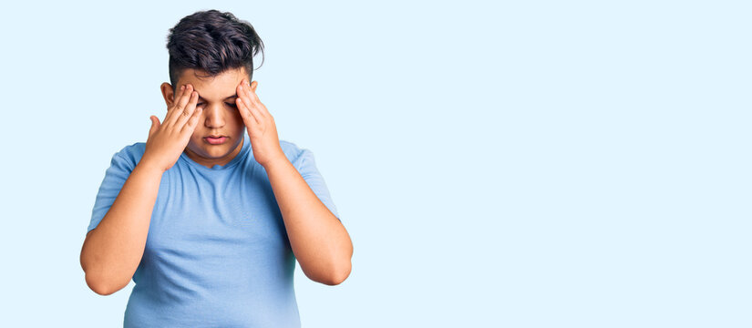Little boy kid wearing sports workout clothes with hand on head for pain in head because stress. suffering migraine.