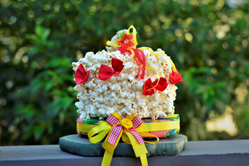 Um bolo decorativo de festa junina de pipoca, laços e fitas coloridas