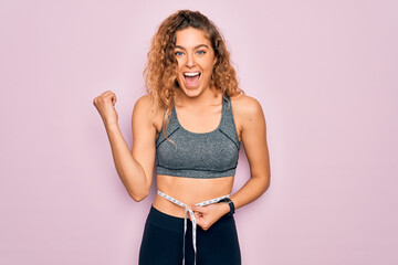 Young blonde sporty woman with blue eyes controlling weight using tape measure on waist screaming...