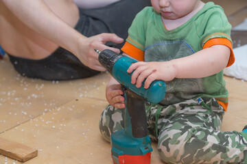 Little boy holds a screwdriver and help his father