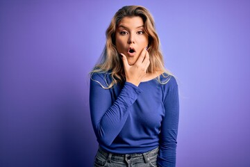 Young beautiful blonde woman wearing casual t-shirt over isolated purple background Looking fascinated with disbelief, surprise and amazed expression with hands on chin