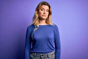Young beautiful blonde woman wearing casual t-shirt over isolated purple background depressed and worry for distress, crying angry and afraid. Sad expression.