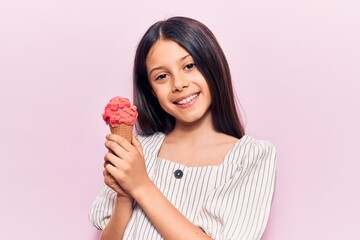 Beautiful child girl holding ice cream looking positive and happy standing and smiling with a...