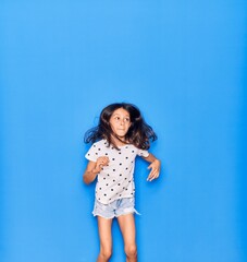 Adorable hispanic child girl wearing casual clothes smiling happy. Jumping with smile on face over isolated blue background