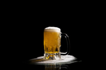 Refreshing, frothy stream of beer, filling a glass mug, beer spilling from the jar to the base, on a black background, celebration of the International Beer Festival.

