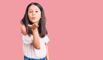 Beautiful child girl wearing casual clothes looking at the camera blowing a kiss with hand on air being lovely and sexy. love expression.