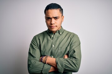 Young brazilian man wearing casual shirt standing over isolated white background skeptic and...