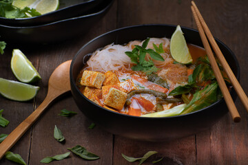 Thai vegan red curry woth tofu, noodles, beans and carrots on wooden table