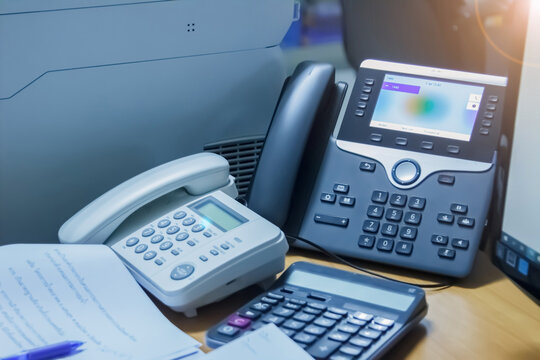 Close up soft focus on telephone devices with copy space background at call center office desk in workspace room and computer for customer service support communication & technology concept.