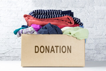 Box of clothing for donation against white wall. Donation box in room. Concept donation.