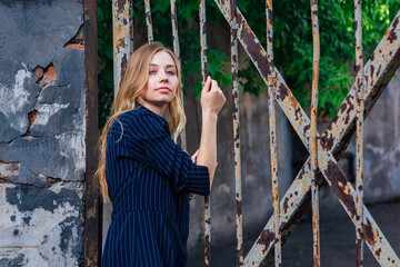 Close up portrait of a fashion look's woman near the old rusty gate. Young woman modern portrait.