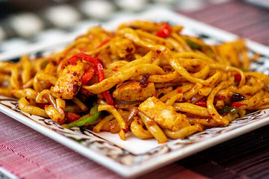 Traditional Central Asian Uyghur dry stir fried noodle dish, Korma Chop. Signature fried noodles with chives, tofu, onions, and red bell peppers.