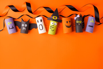Halloween and decoration concept - monsters from toilet paper roll tube on orange. Simple easy diy...