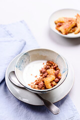 Healthy breakfast yogurt bowl with granola and caramelized bananas and nuts on grey concrete background. Selective focus