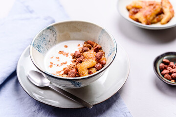 Healthy breakfast yogurt bowl with granola and caramelized bananas and nuts on grey concrete background. Selective focus