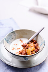 Healthy breakfast yogurt bowl with granola and caramelized bananas and nuts on grey concrete background. Selective focus